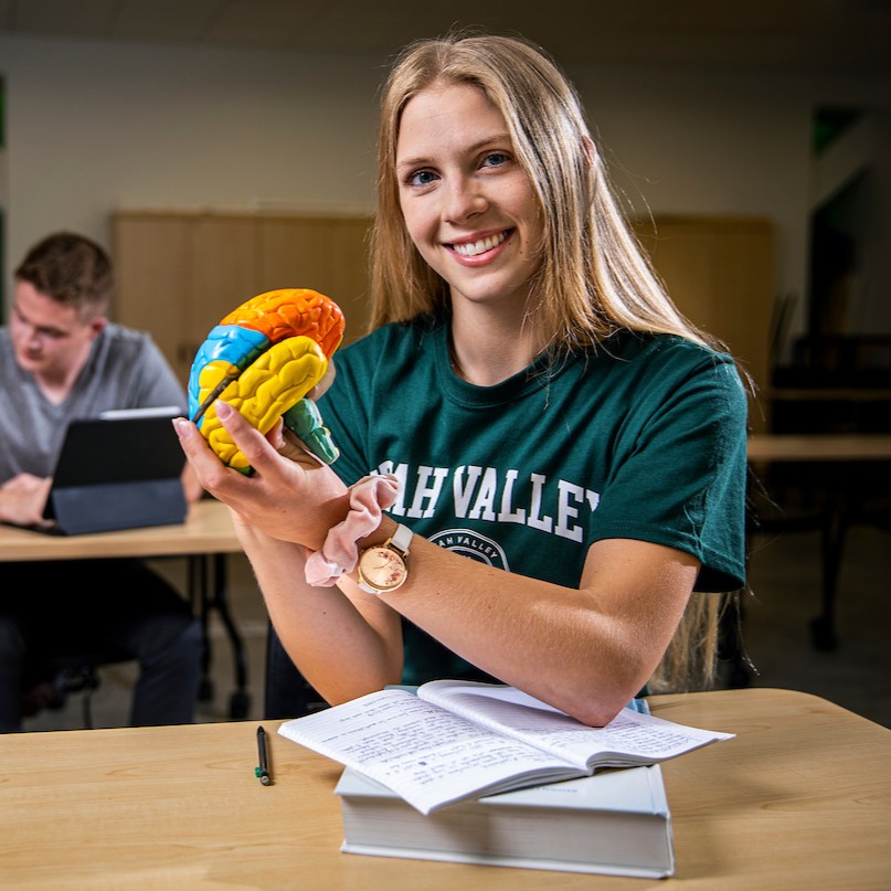 student holding a diagram of a brain