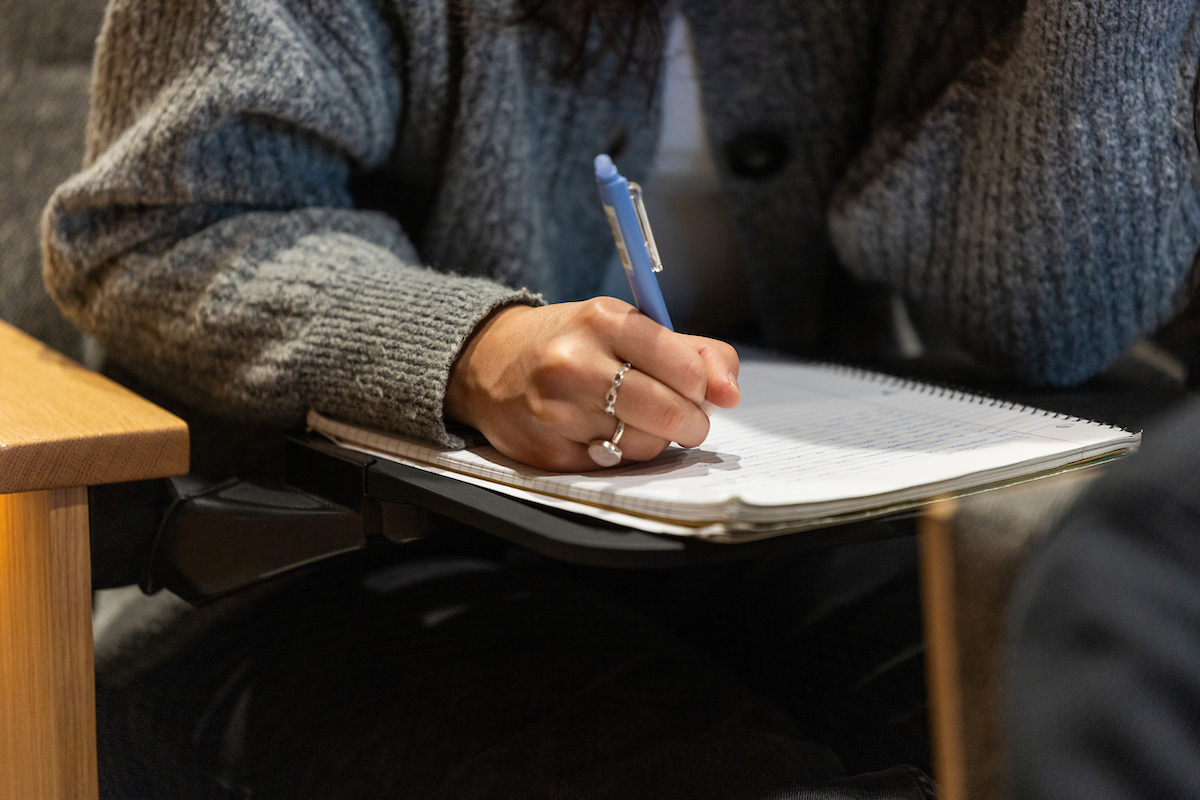 person writing notes at their desk