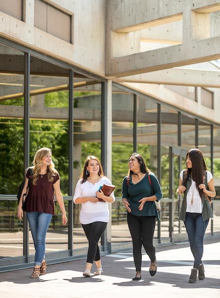 A group of four woman walking outside talking with each other.