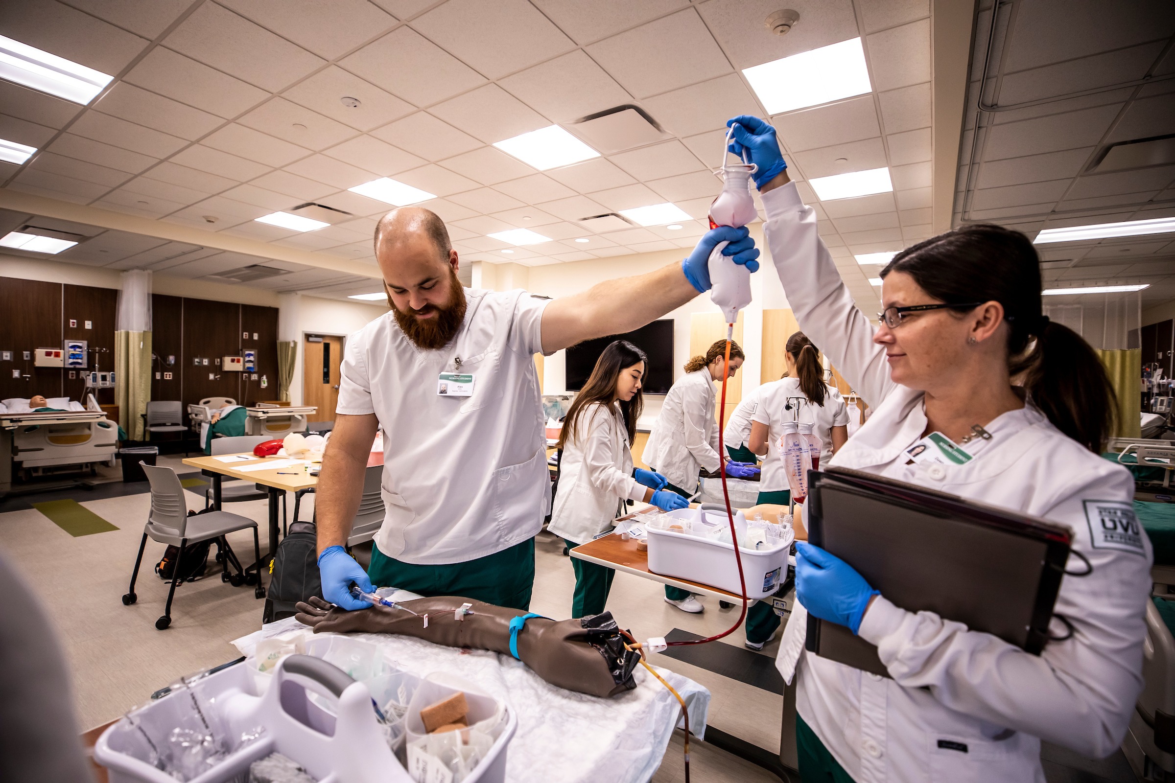 Students practice administering IV fluids on a medical dummy.