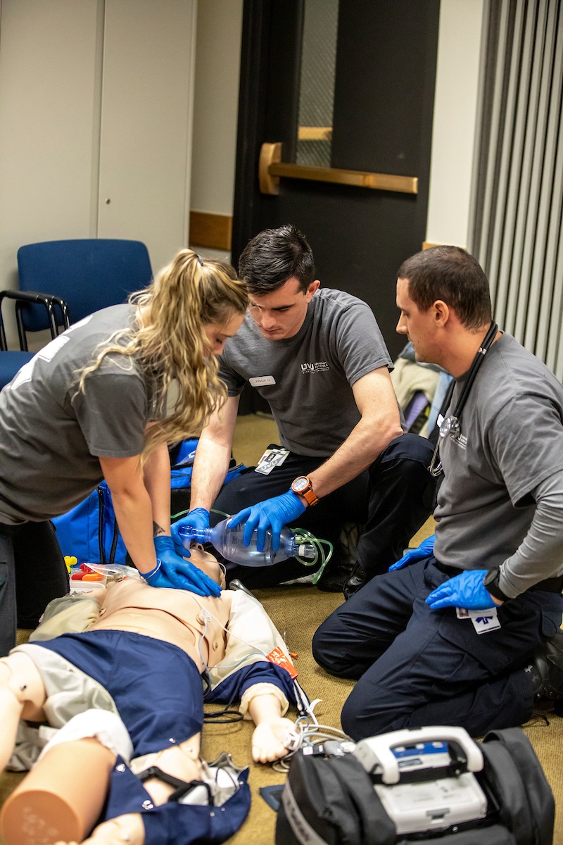 Group of paramedic students performing CPR on a medical dummy.