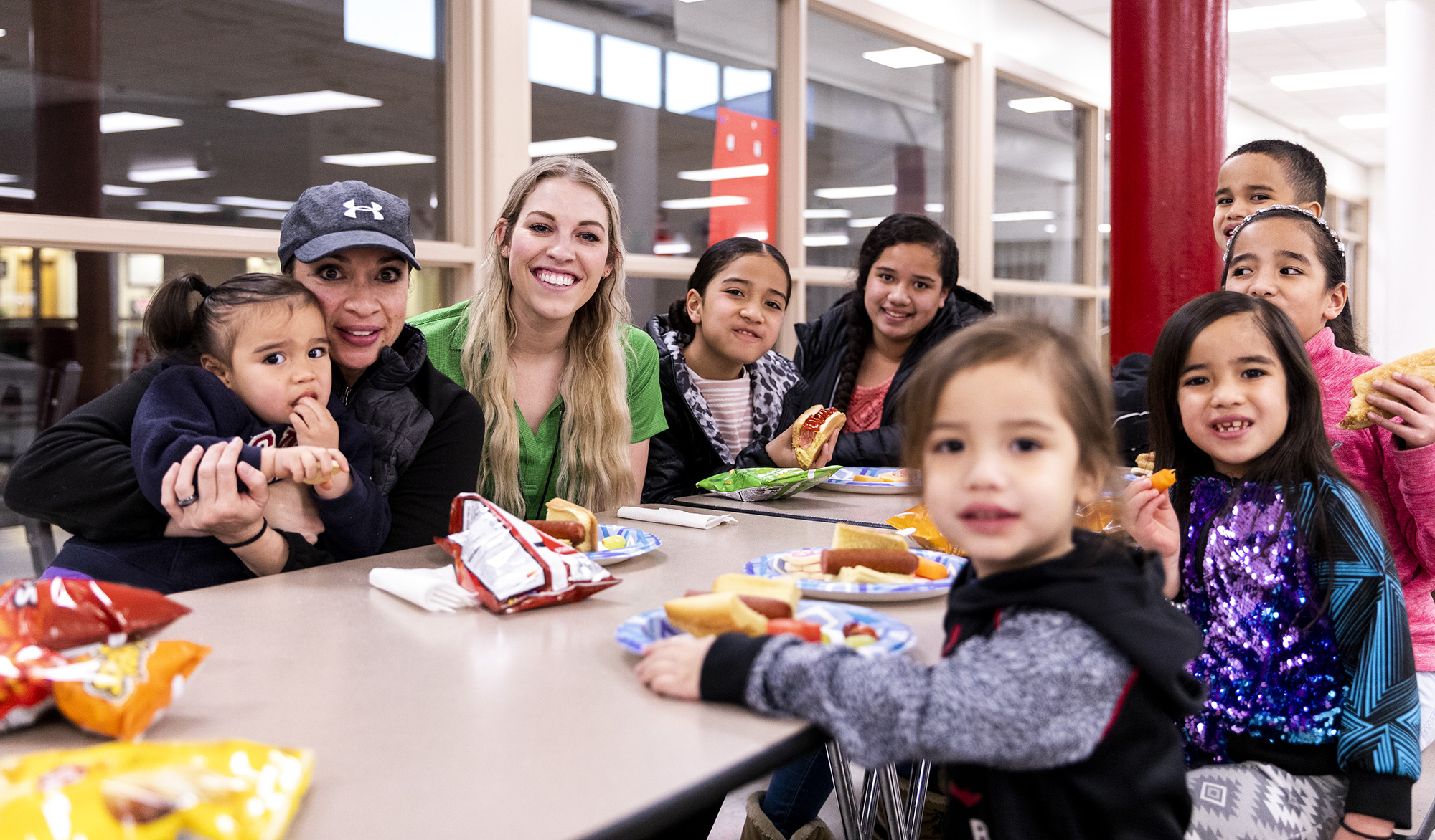 A group of adults and youg children sitting around a table.