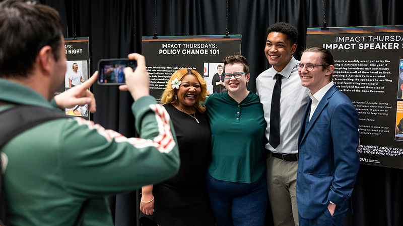 students pose for picture in front of their social impact presentations