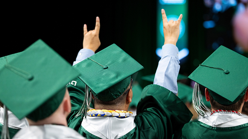 graduation raising hands in celebration during ceremony