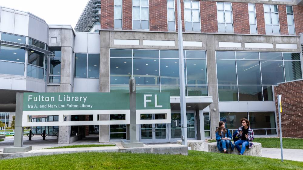 students sitting and talking in front of the fulton library