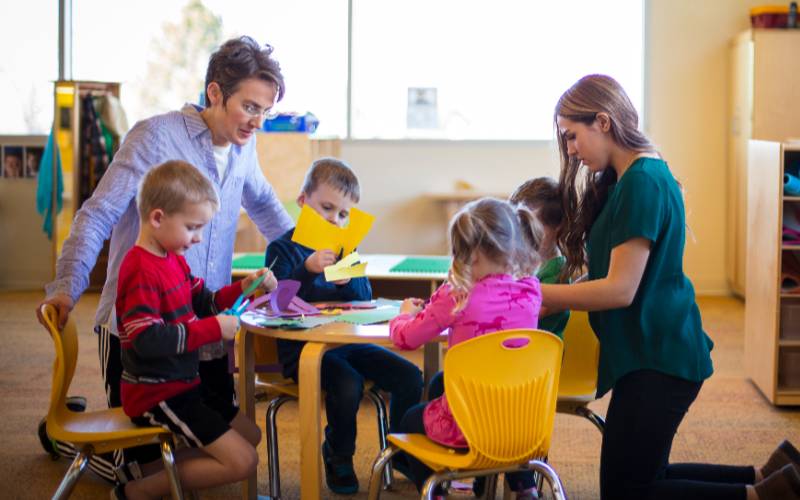 childcare workers helping children with arts and crafts