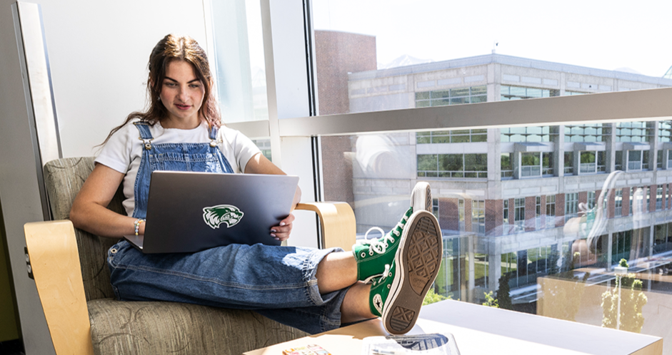 female student sitting on campus working on computer