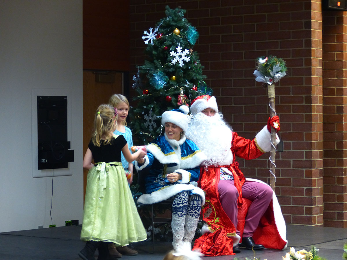 Snegurochka and Ded Moroz pass out New Years treats to children.