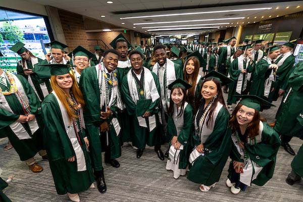 UVU Graduates standing next to each other, smiling at the camera for a pipcture.