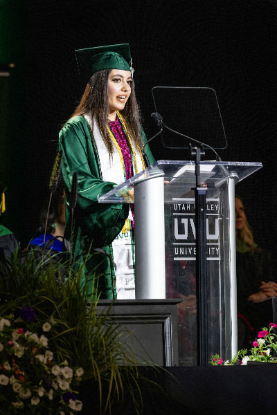 Commencement Speaker at podium dress in UVU graduate attire.
