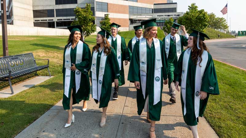 Graduates walking in a group together, dressed in UVU graduation attire.