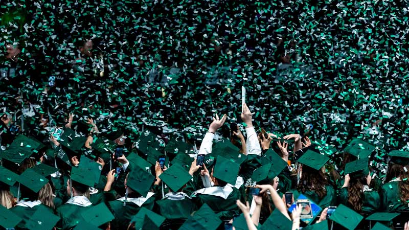 Graduates cheering with confetti falling around