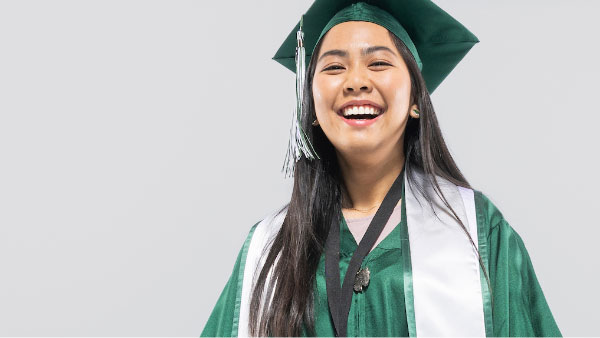 Woman dressed in UVU green and white graduation gown and hat