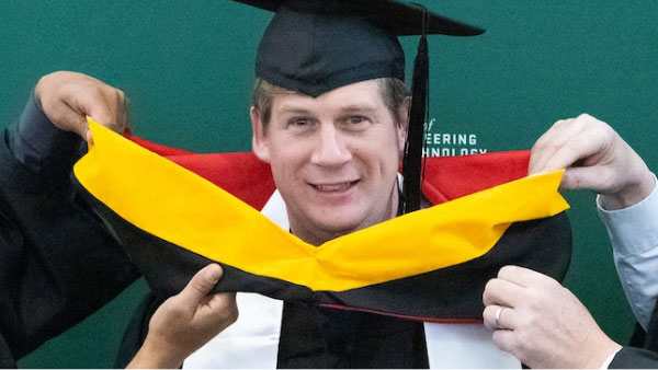 A UVU graduate having an yellow and red sash put on them.