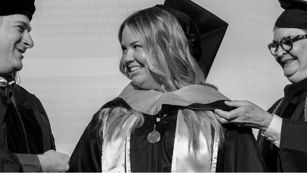 A UVU graduate having a brown sash put on them.