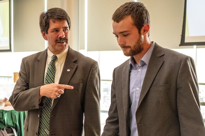 professor directing student, while both dressed in suits