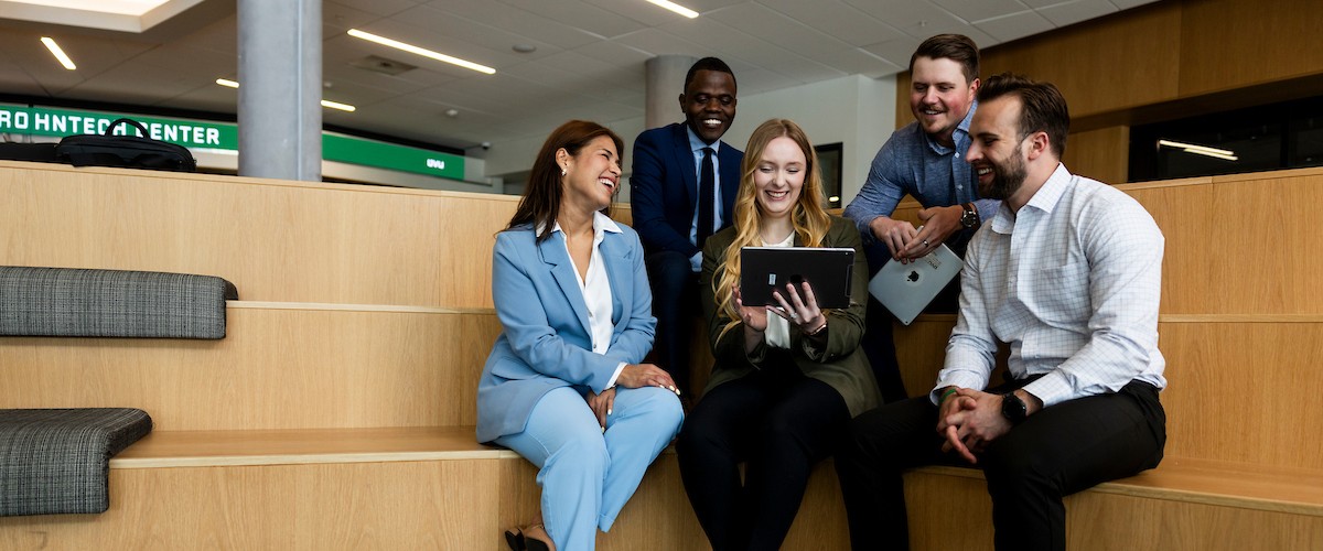 group of business employees seated looking at a laptop in front of them