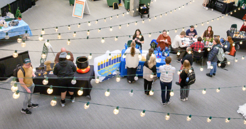 Diverse students experiencing different religions and worldviews at a holiday fair