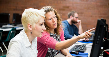 woman helping another woman at a computer