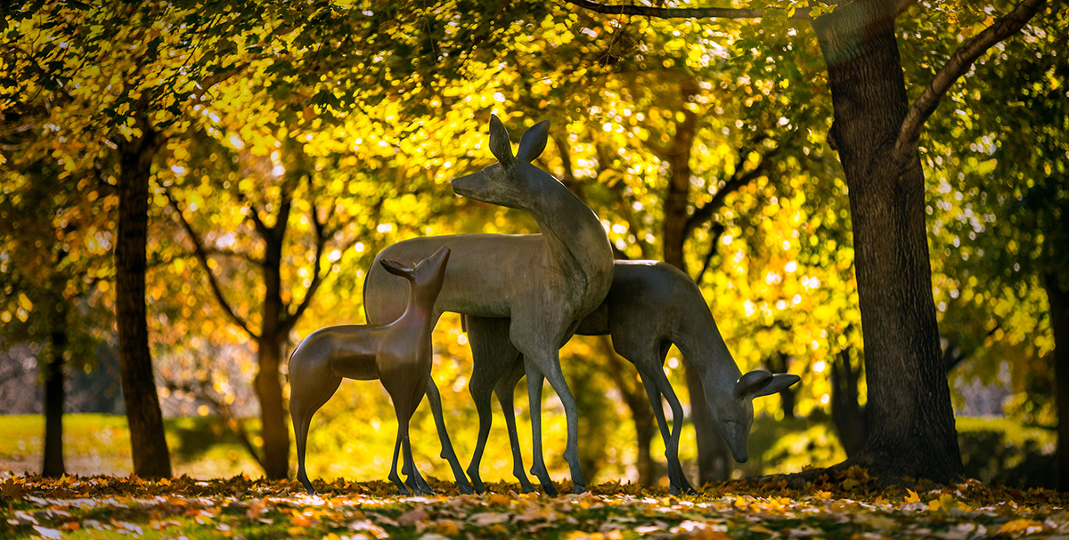 Campus deer statue surrounded by yellow trees in fall