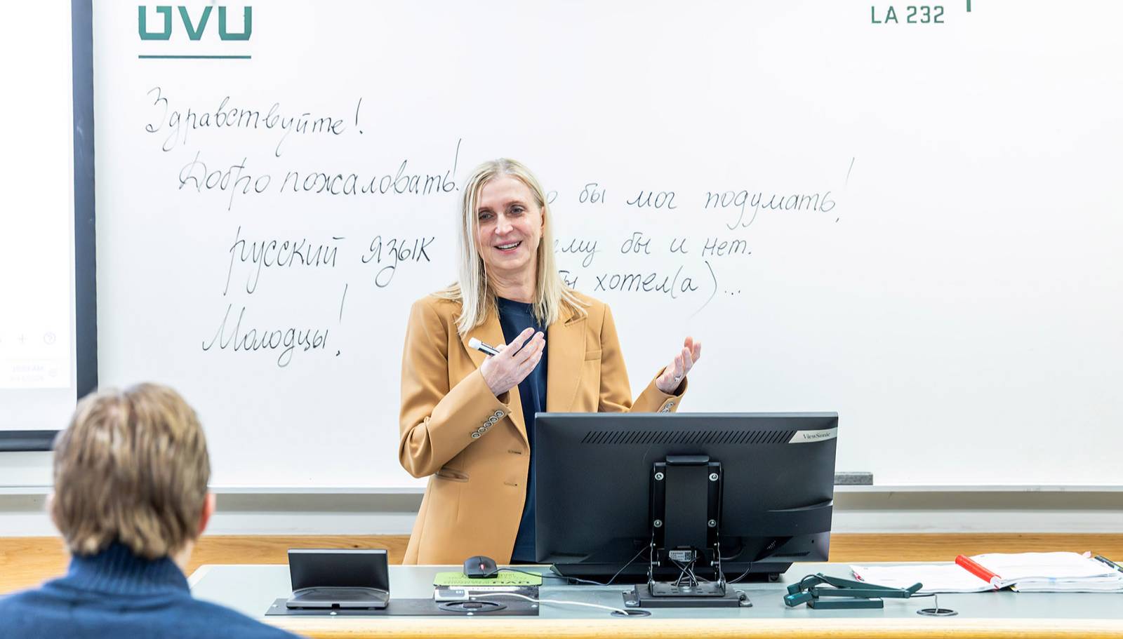 Russian Studies professor Olga Jarrell teaching a class, with Russian on the whiteboard behind her