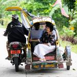 President Tuminez sitting in a rickshaw with someone else