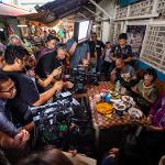 President Tuminez sitting down eating food with someone while people watch her with camera