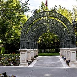 A row of five metal arches surrounded by bright flowers lead to the back gardens