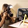 A woman kneels down to take pictures of a knife that is on a desk in the crime scene house