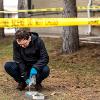 A man crouches down outside near a cast he is making of a footprint in the dirt