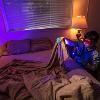 A man uses a UV light in a darkened room to look for fluids on a blanket