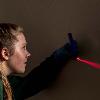 A woman holds a tool against a wall that projects a laser from it
