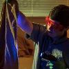 A man holds up a blanket to a UV light to look for fluids that might be on a blanket