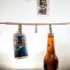Various bottles and cans hang from clips attached to a string in front of a light