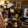 A man uses a machine to look at a piece of metal up close