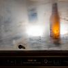 Close up of a bottle in a machine behind a dirty pane of glass