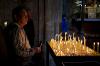 A photo of a person in front of a cathedral altar that is covered in candles.