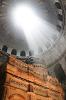 A photo of a beam of sunlight shining through an opening in the top of an ancient structure.