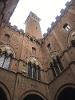 A photo taken from the bottom of a courtyard. It depicts the top of the surrounding buildinds and the white sky.