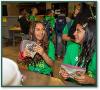 Two girls wearing green shirts looking at each other and laughing