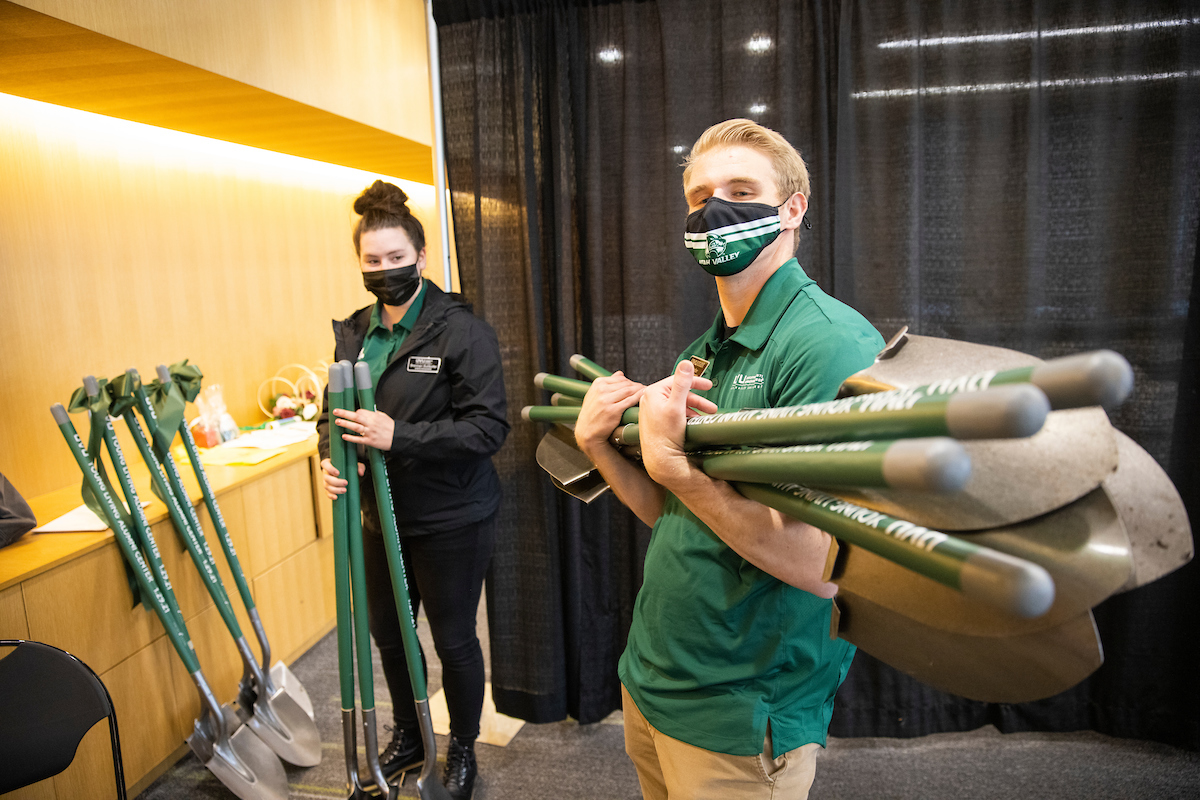 Two event ambassadors prepare shovels for the Alumni House groundbreaking.