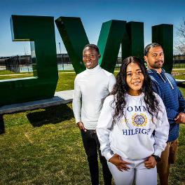 Three people standing in front of UVU sign