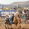 Rodeo member jumping from a horse and on to a calf
