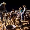 Rodeo members sitting on horses and on a fence talking
