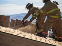 Firefighter cutting through plywood with a chainsaw