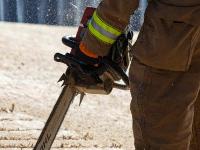 Firefighter cutting through plywood with a chainsaw