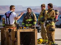 A group of firefighters being instructed by another firefighter without gear