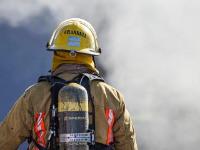 Firefighter carrying a firehose looking a smoking building