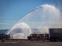 Two firetrucks with one firetruck spraying water.