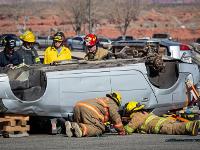 A group of firefighters looking at an overturned car